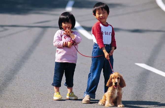 写真:犬の散歩をする男の子と女の子