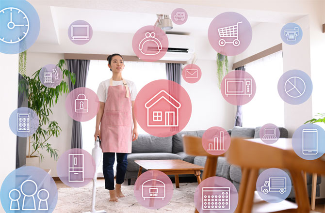 写真:IOTイメージ リビングにいる主婦とショッピングカート、時計、配達トラックのアイコン