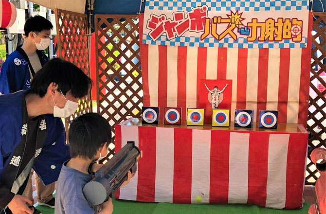 写真:ジャンボバズーカ射的をする男の子